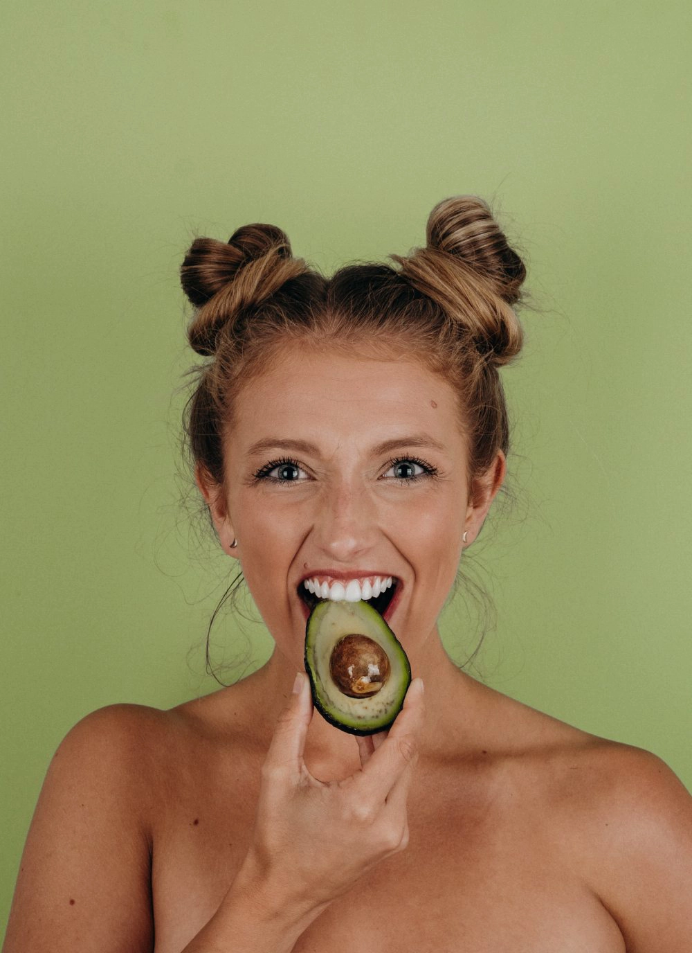 Girl eating a healthy avocado, rich in good fats and nutrients.